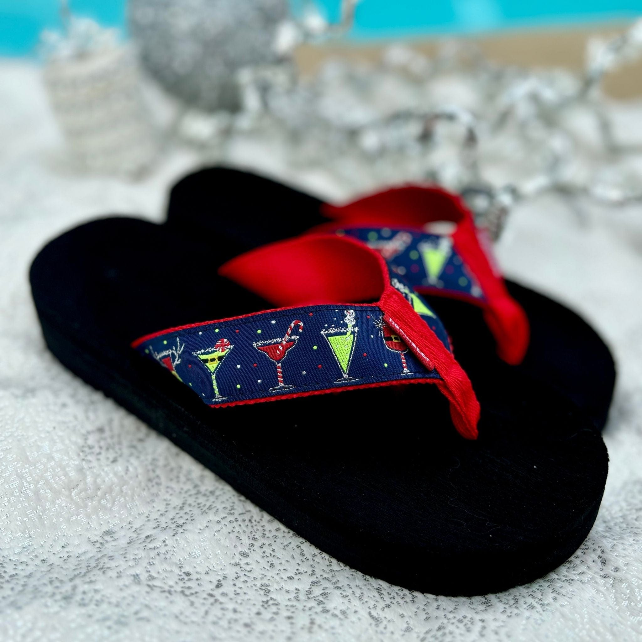 Black flip-flops featuring a festive cocktail print on the straps, perfect for holiday gatherings and celebrations.