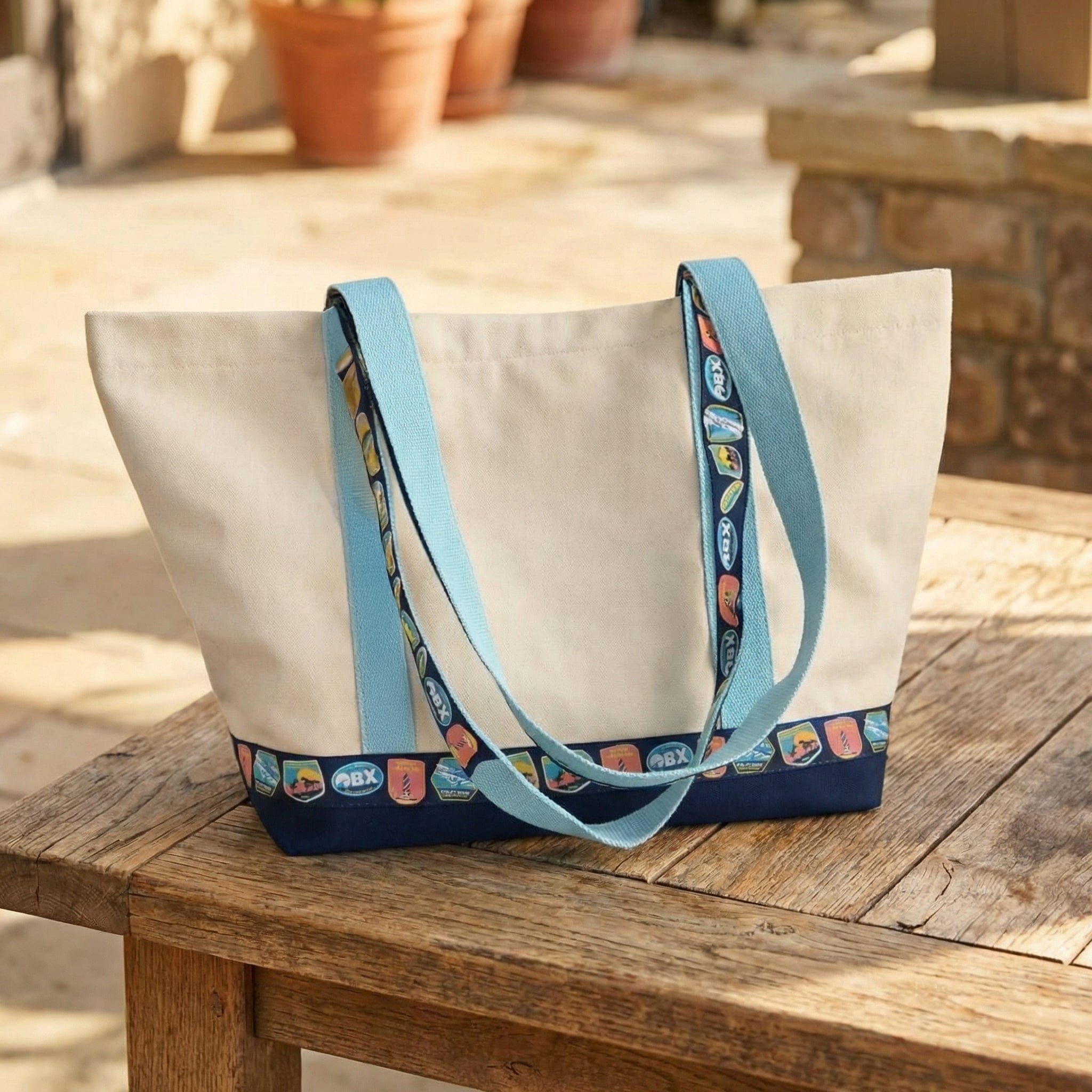 White tote bag with blue handles and trim on a wooden surface outdoors