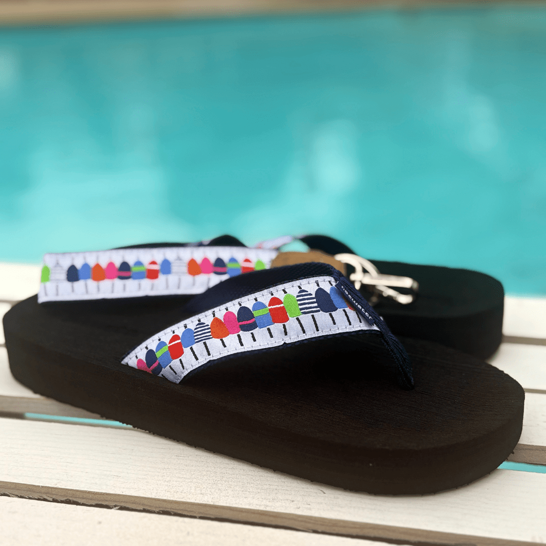 Colorful flip-flops with a buoy-themed strap design, set against a poolside background. Ideal for summer fun.