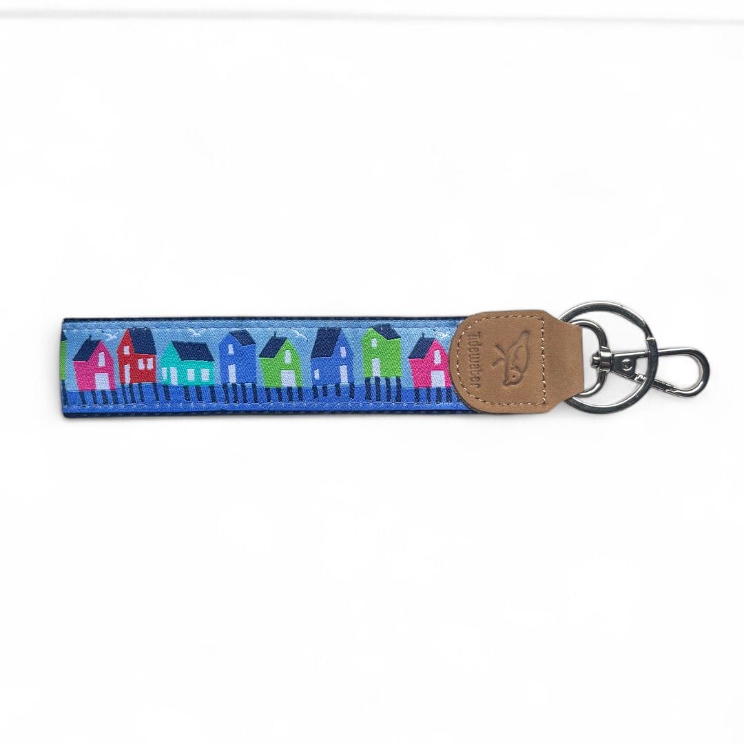 Colorful keychain featuring a design of vibrant houses in blue, green, and pink with a leather tag and metal keyring.