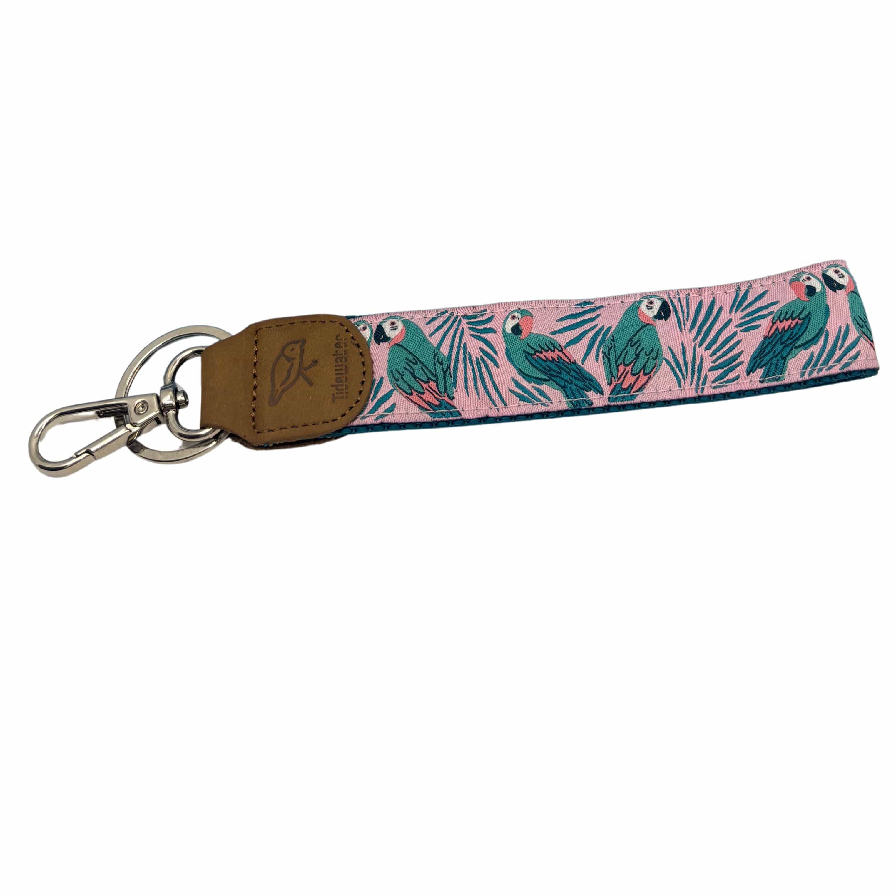 Colorful keychain featuring a parrot design on a pink background with green leaves, finished with a metal clip and leather tag.