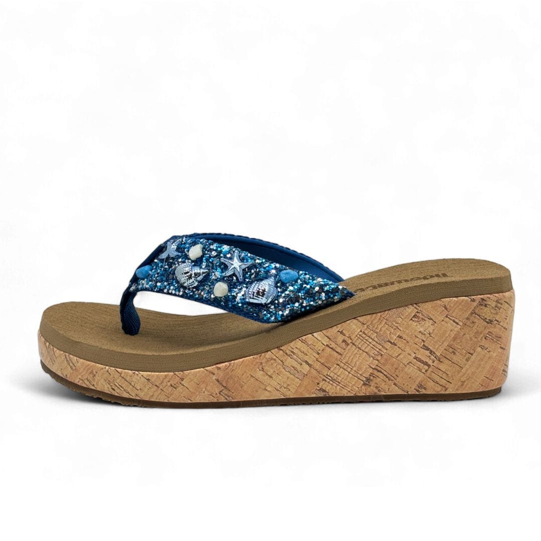 Side view of women’s blue wedge flip flop with cork platform and seashell embellished glitter strap