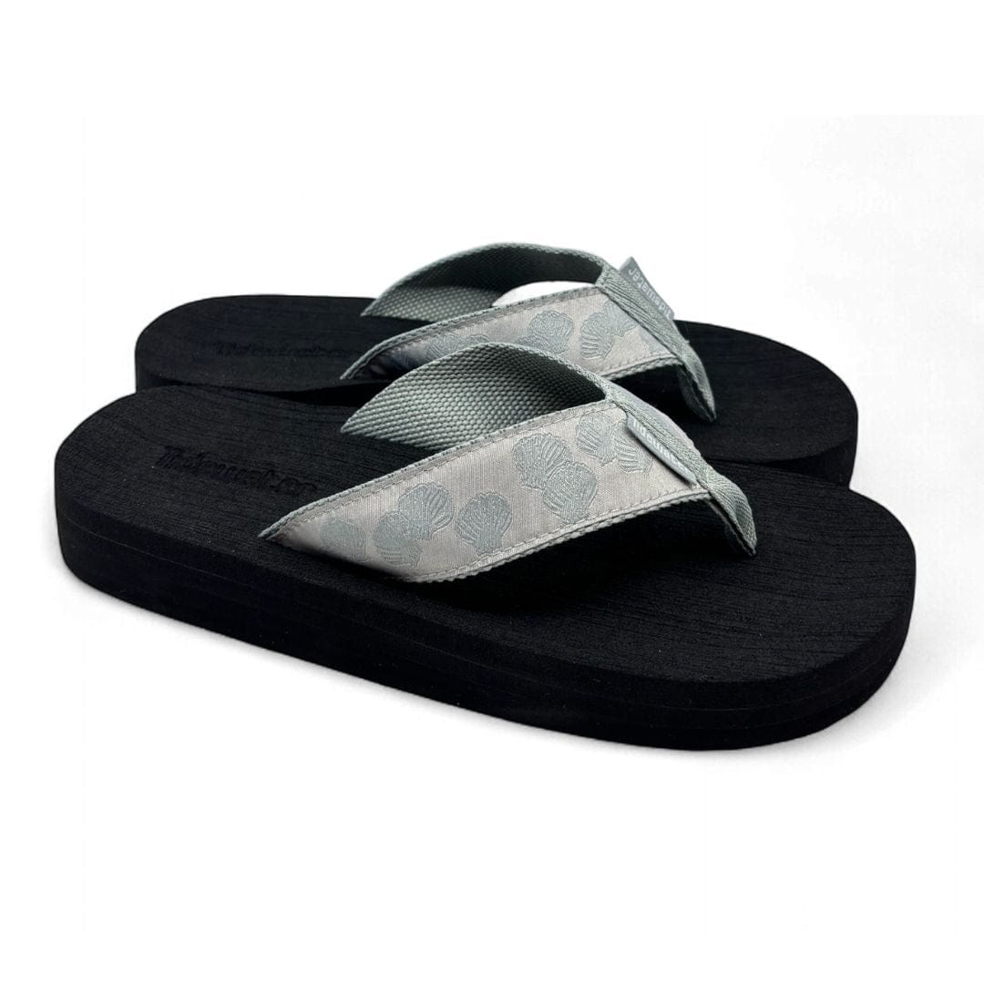 Black sandals with gray seashells straps on a white background